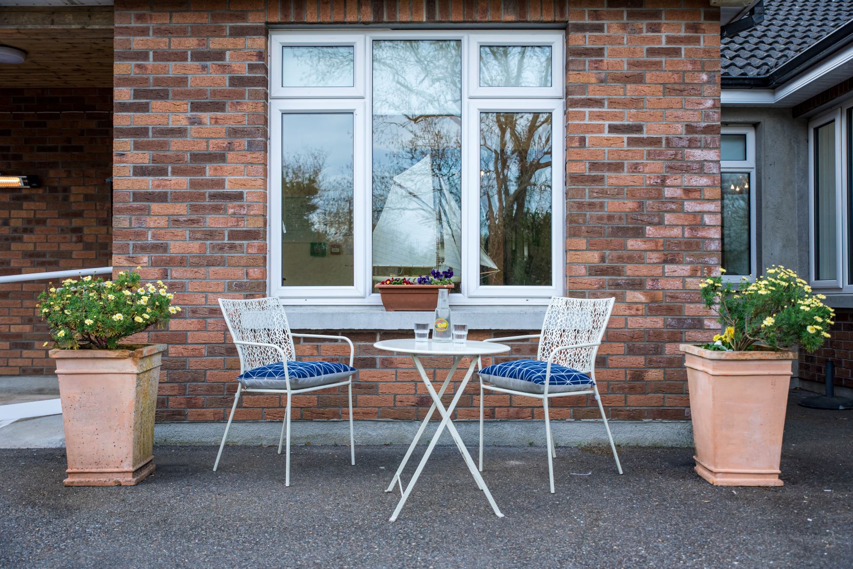 An outdoor garden table and two small chairs looking out into the front yard.